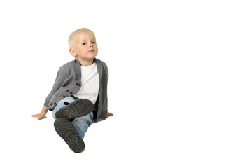 Cute little blond boy sits on floor and looking isolated on white background with copy space for text or advertising