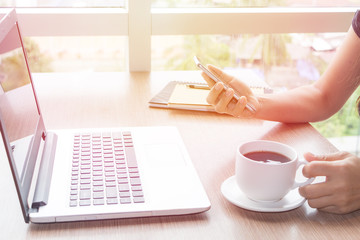 Close Up of woman hands using mobile phone and laptop computer business with blank copy space screen for your business advertising text message or content business in the morning light.