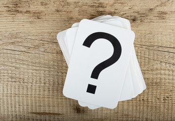 Stack of cards with a question mark on wooden background