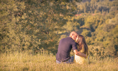 Naklejka na ściany i meble kissing young couple back rear view outdoors sunny forest mounta