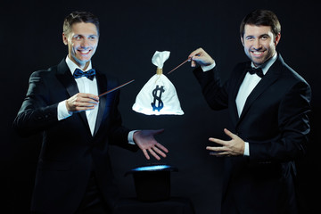 Two magicians taking sack with money out of top hat