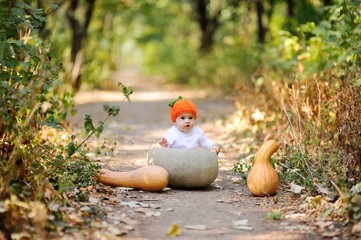 child celebrating Halloween in the middle of autumn forest. Girl sits inside a huge pumpkin