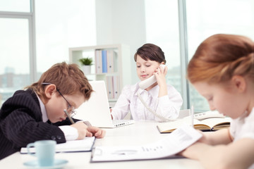 Fototapeta na wymiar Three cute children working in office 