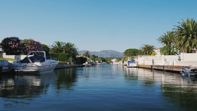 POV video sail on a boat through the channel with the elite real estate. Empuriabrava, Spain, Catalonia. In the background are visible mountains