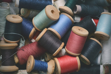 Vintage hipster background of plenty multicolor threads bobbins top view. Atelier, sewing accessories backdrop.