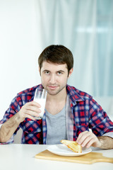 Fototapeta na wymiar Portrait of a man eating sandwich and washing it down with milk