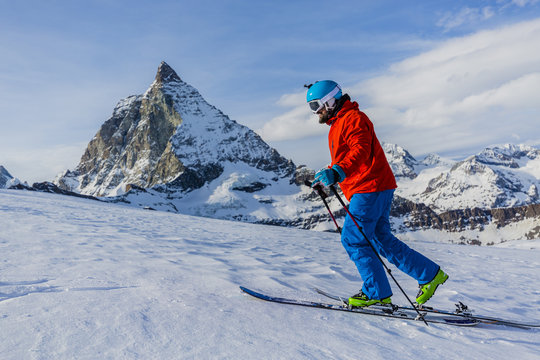 Ski touring man reaching the top in Swiss Alps. Matterhorn in th