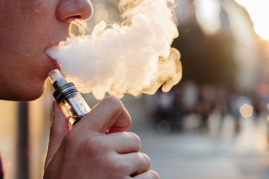 man using vape or electronic cigarette against the background of