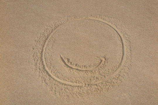 Symbol "smile" on beach background drawing shape on sand