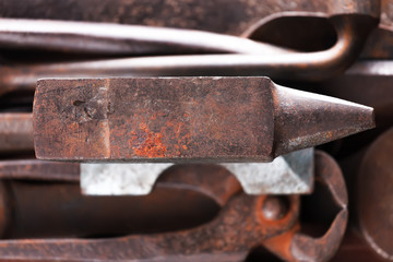 Old rusty rugged anvil on other blacksmith tools.