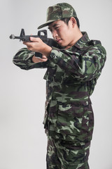 Asian soldier in green camouflage uniform with long gun - Soft Focus