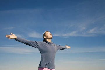 Young woman enjoying spring breeze on the sky bg