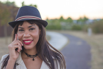 Close-up of a beautiful young woman with hat talking on the mobile phone.