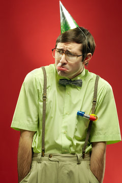 Portrait of nerd in party hat pouting like a child