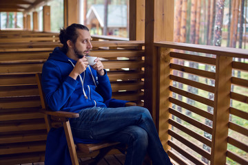 guy in a blue jacket with hood draped on his head sitting chair