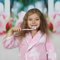 Little girl in pink bathrobe going to brush teeth