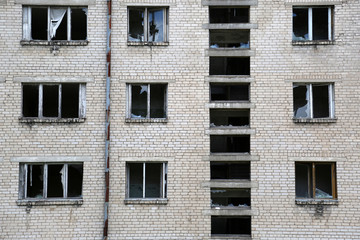 Fototapeta premium Abandoned building wall with broken windows background - ruins of dwelling house