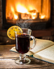 Hot mulled wine and a book on the wooden table.