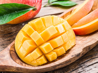 Mango fruit and mango cubes on the wooden table.