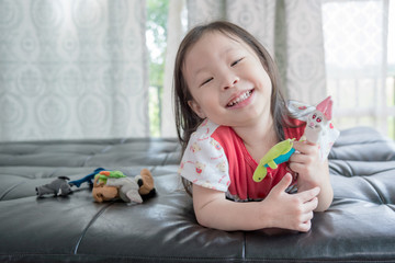 Little asian girl playing with animal puppets on sofa