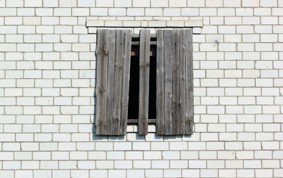 Boarded up window in a white brick wall