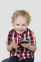 Little boy plays with smartphone on gray background - Modern gadgets and communication concept - Simplicity and usability