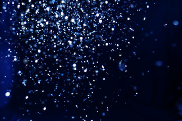 Christmas and holiday background. Blue glowing abstract glitter on black