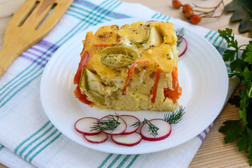 A piece of casserole of vegetables (zucchini, carrots) on a white plate. Vegetarian dish.