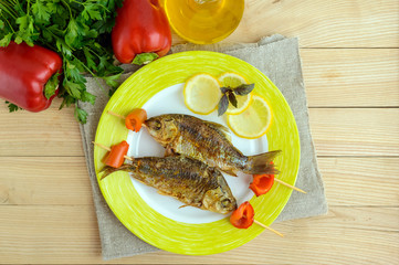 Fried fish (carp) on skewers with pieces pepper and lemon. The top view