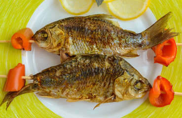 Fried fish (carp) on skewers with pieces pepper and lemon. The top view. Close up