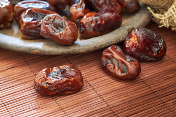 Dried dates fruit in rustic plate on wooden background