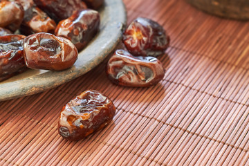 Dried dates fruit in rustic plate on wooden background. Copy space