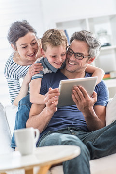a cheerful family has fun together by playing on a tablet