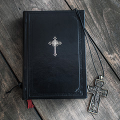 Christian cross necklace next to holy Bible
