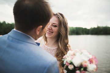 Happy wedding couple hugging and smiling each other on the background lake, forest