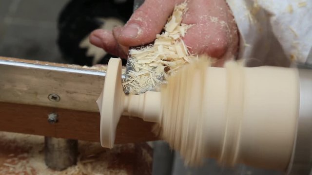artisan shapes the piece of wood with a fine chisel and lathe that spins faster