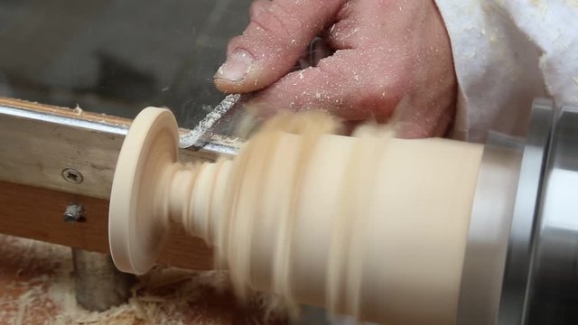 artisan shapes the piece of wood with a fine chisel and lathe that spins faster