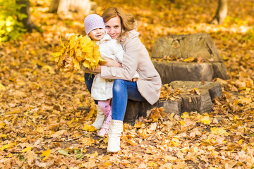 Naklejka premium happy family: mother and child little daughter play, laughing cuddling on autumn walk in nature outdoors