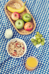 Obraz na płótnie Canvas Cereales, frutas, vaso de zumo de naranja y yogur sobre un mantel a cuadros azul y blanco. Vista superior. Concepto: picnic
