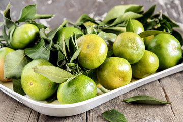 Green tangerine with leaves in tray