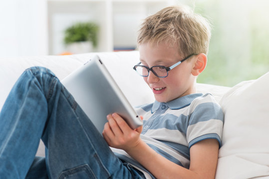 At home, 8 years old boy having fun by surfing on a tablet