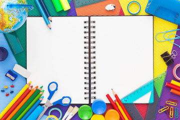 Colorful background with school supplies and open notebook. 