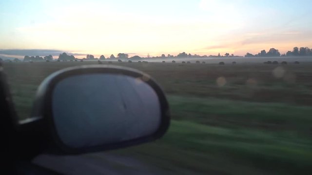 Car driving through agricaltural field. Surise. Golden sky