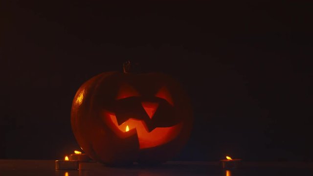CU Halloween carved pumpkin Jack-o-Lantern with candles on dark background