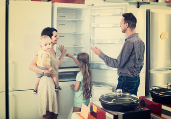 family of four shopping new refrigerator in home appliance store
