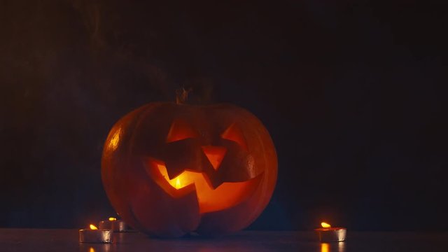 CU Halloween carved pumpkin Jack-o-Lantern with candles, fog in the background