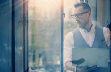 Young Bearded Businessman Wearing Glasses White Shirt Waistcoat Holding Modern Laptop Hands Looking Open Panoramic Windows.Man Working Office Startup Project Workplace.View Through Window.Blurred.