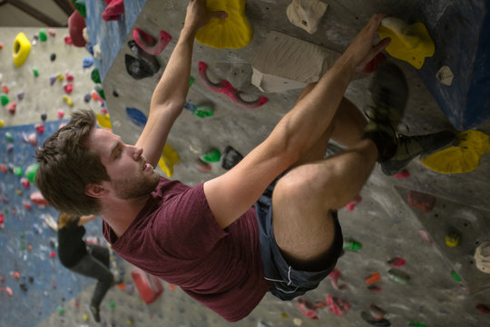 young man climbing in a boulder hall