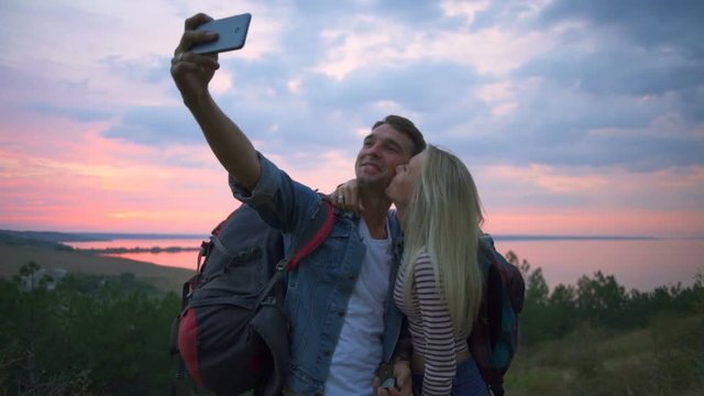 Couple smiling kissing making selfie on hill at sunrise Slow motion