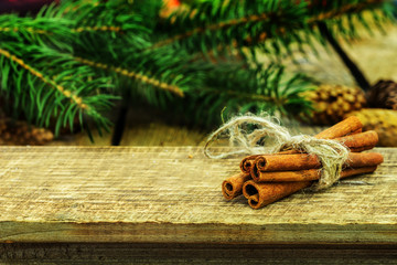 Rustic Christmas wooden background with cinnamon sticks and fir tree.